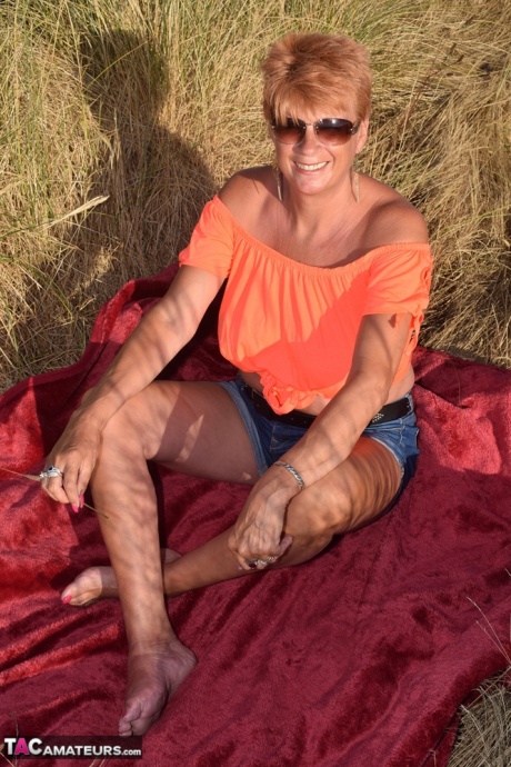 Зрелая рыжеволосая Димонти показывает свои сиськи на скамейке в загородном поле 20