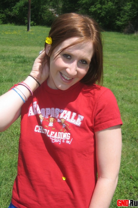 Молодо выглядящая рыжеволосая красотка демонстрирует свои сиськи и нижнее белье на футбольном поле 8