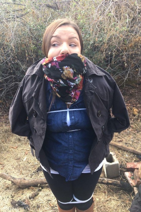 Полностью одетый толстяк расколот, с кляпом во рту и связанный веревкой в заросшем кустарником лесу 2