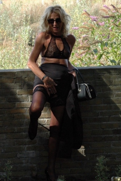 Зрелая блондинка Кирас Нейлонс позирует на шпильках в чулочно-носочных изделиях и черной юбке 15