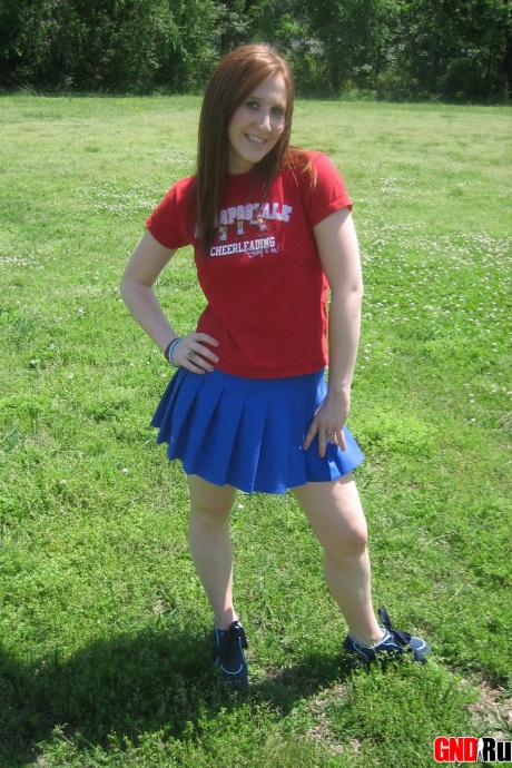 Молодо выглядящая рыжеволосая красотка демонстрирует свои сиськи и нижнее белье на футбольном поле 1