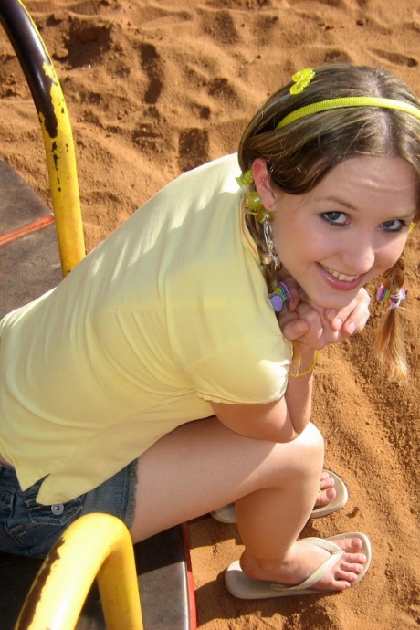 Симпатичная девушка обнажает свой лифчик и трусики под юбкой на детской площадке 2