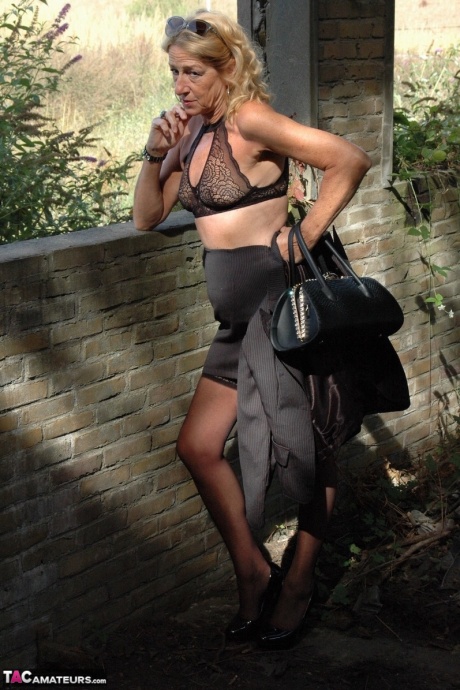 Зрелая блондинка Кирас Нейлонс позирует на шпильках в чулочно-носочных изделиях и черной юбке 8