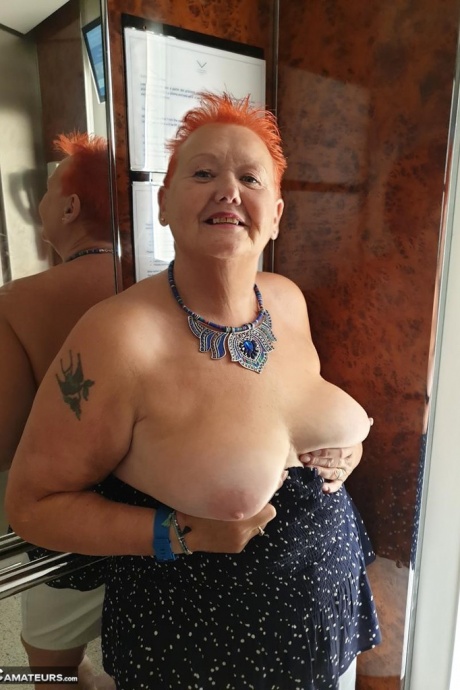 Толстая бабуля с короткими рыжими волосами прижимается своими большими сиськами и задницей к стеклу 1