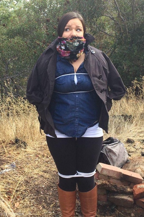 Полностью одетый толстяк расколот, с кляпом во рту и связанный веревкой в заросшем кустарником лесу 3