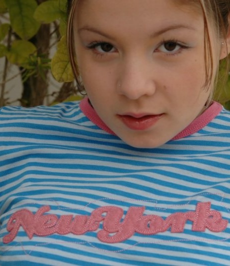 Молодо выглядящая девушка снимает прозрачные трусики, раздеваясь во внутреннем дворике в саду 1