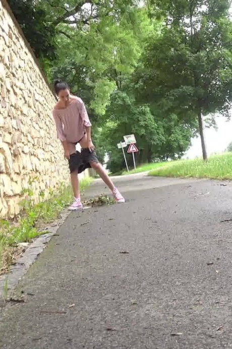 Коротко снятая девушка Мистика садится на корточки, чтобы пописать, на мощеной дорожке в городской обстановке 13