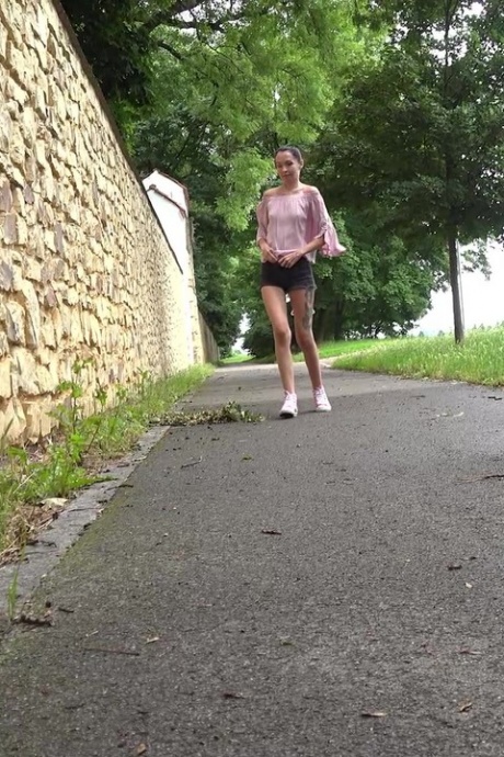 Коротко снятая девушка Мистика садится на корточки, чтобы пописать, на мощеной дорожке в городской обстановке 1