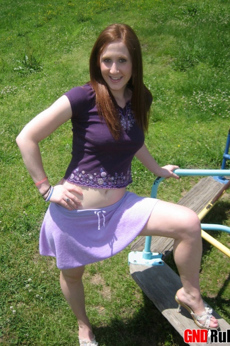 Молодая рыжеволосая красотка демонстрирует свою грудь и трусики на детской площадке 1