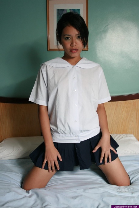 Горячая азиатская школьница снимает свою униформу, чтобы потереться своей лысой киской о кровать
